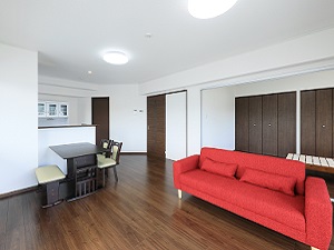 備付家具冷暖房完備の日当たり良い院外宿舎室内（他にベッドルームあり、ソファの色は黒と赤から選択可）